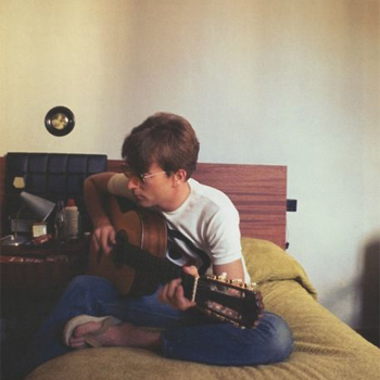 John Lennon Playing Guitar on the Bed