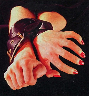 Woman Wearing Red Nail Varnish with Wrists Strapped in Black Leather Belt